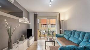 A modern living room with a sofa, TV, and decorative items on a white console.