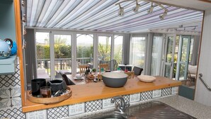 Une cuisine moderne dotée d’un grand îlot central, d’un évier et offrant une vue sur l’extérieur grâce à de grandes fenêtres.