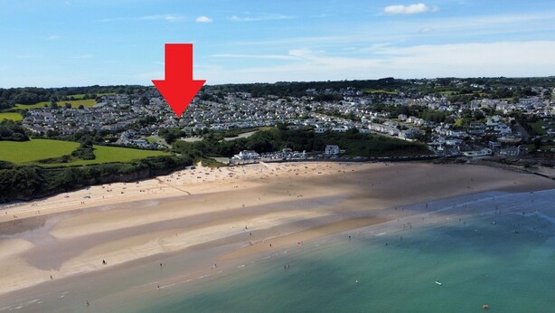 Une vue aérienne d’une ville côtière avec une plage, des maisons et une vaste étendue d’eau.