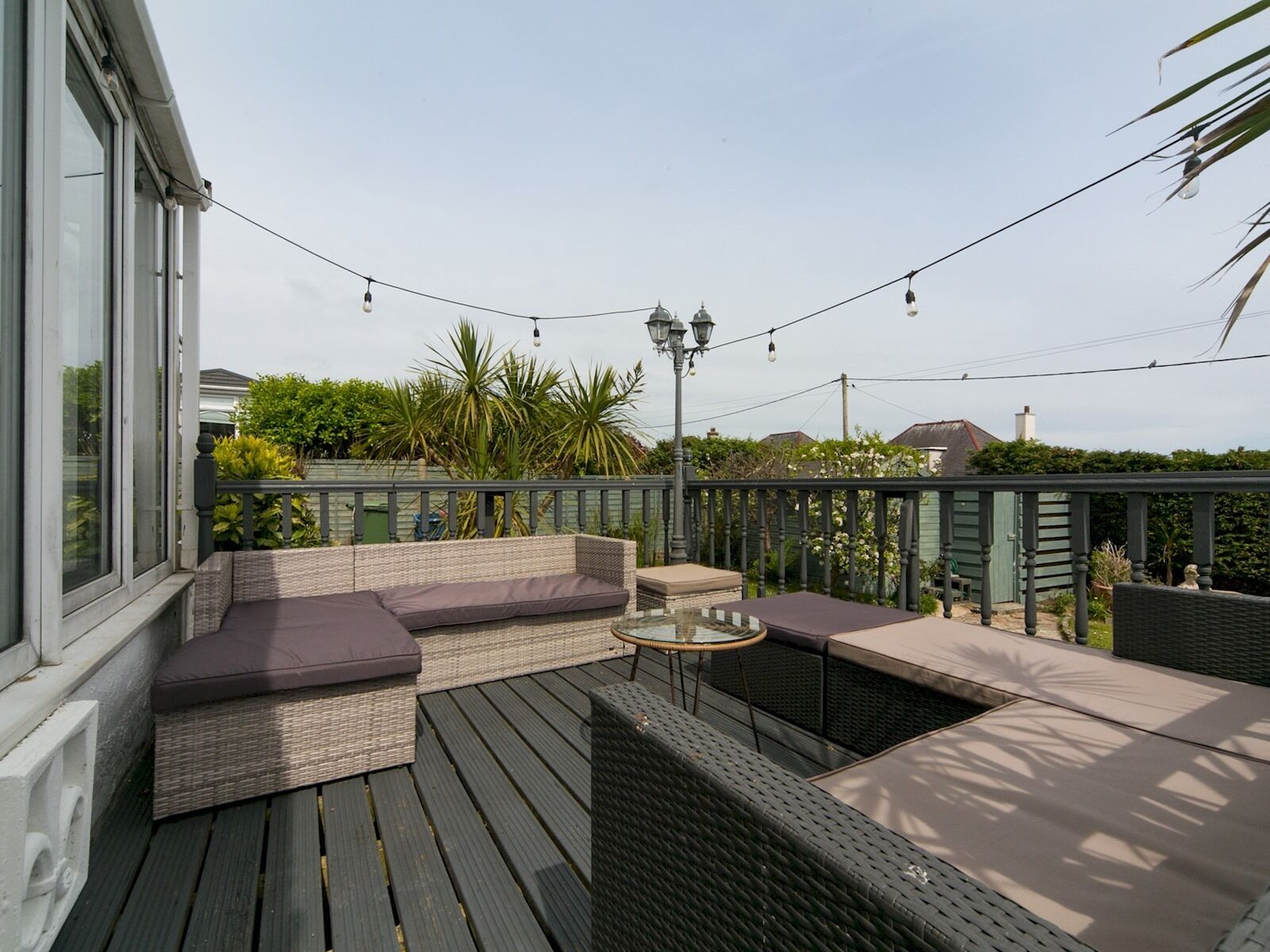 Une terrasse extérieure dotée d’un espace salon, de guirlandes lumineuses et d’une pergola.