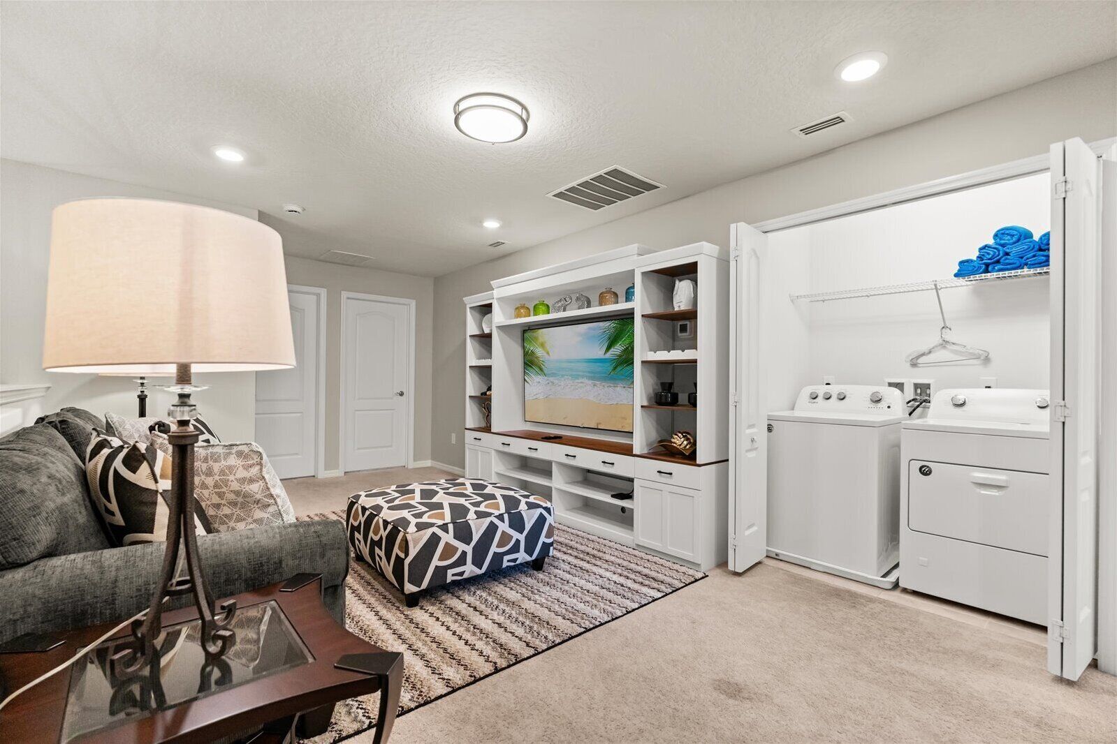 A living room with a sofa, ottoman, coffee table, TV, and built-in shelving.