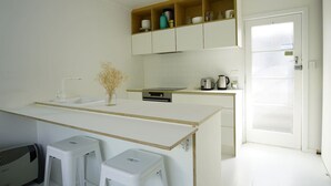 A modern kitchen with white cabinetry, a central island, and a built-in oven.