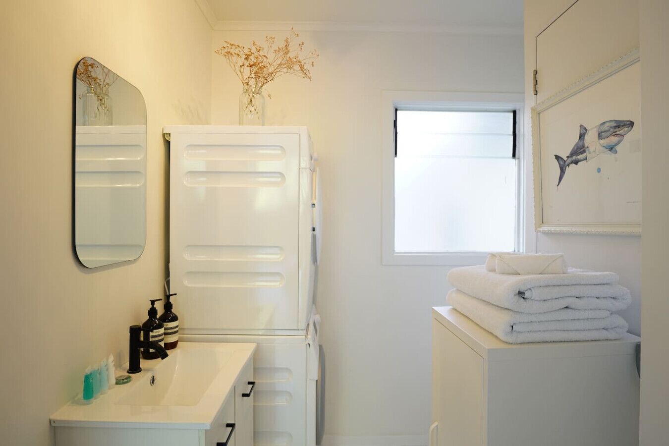 Une salle de bain avec un lavabo blanc, un miroir et une pile d’serviettes.