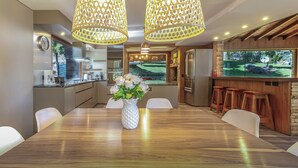 A modern kitchen with a large island, a dining area with a wooden table, and a bar with stools. - Apartments Bariloche - Lago Gutierrez (San Carlos de Bariloche)