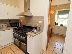 Una cocina moderna con estufa a gas, horno y microondas. Hay armarios, una encimera y una ventana con vistas.