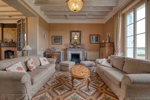 Un salon doté d’une cheminée, d’un parquet à motifs et d’un lustre.