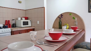 A kitchen with a dining table set for four, equipped with red and white plates, bowls, and cutlery. - Stay 5 min from the beach and downtown Cancun. (Cancún)