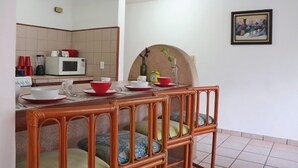 A dining area with a wooden table, chairs, and a kitchen in the background. - Stay 5 min from the beach and downtown Cancun. (Cancún)