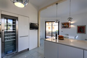 A modern kitchen with a built-in wine cooler, a flat-screen TV, and a dining area with a view of the outside.