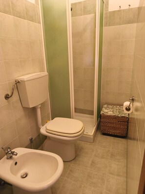 Un baño con inodoro, bidé y cabina de ducha.