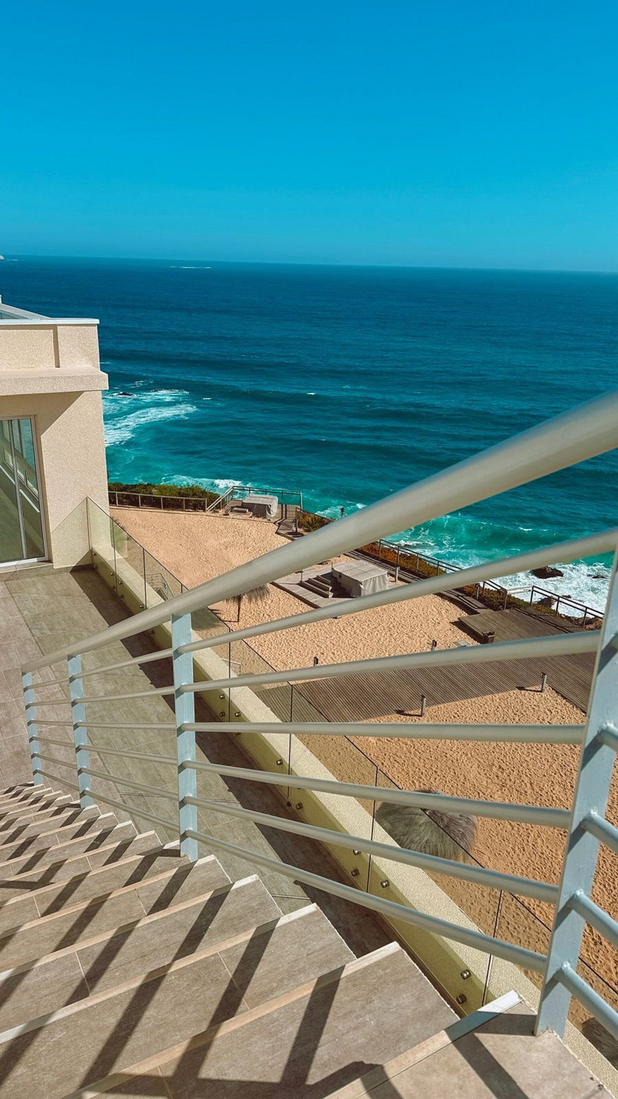 Eine Treppe führt zu einem Strand mit Blick aufs Meer.