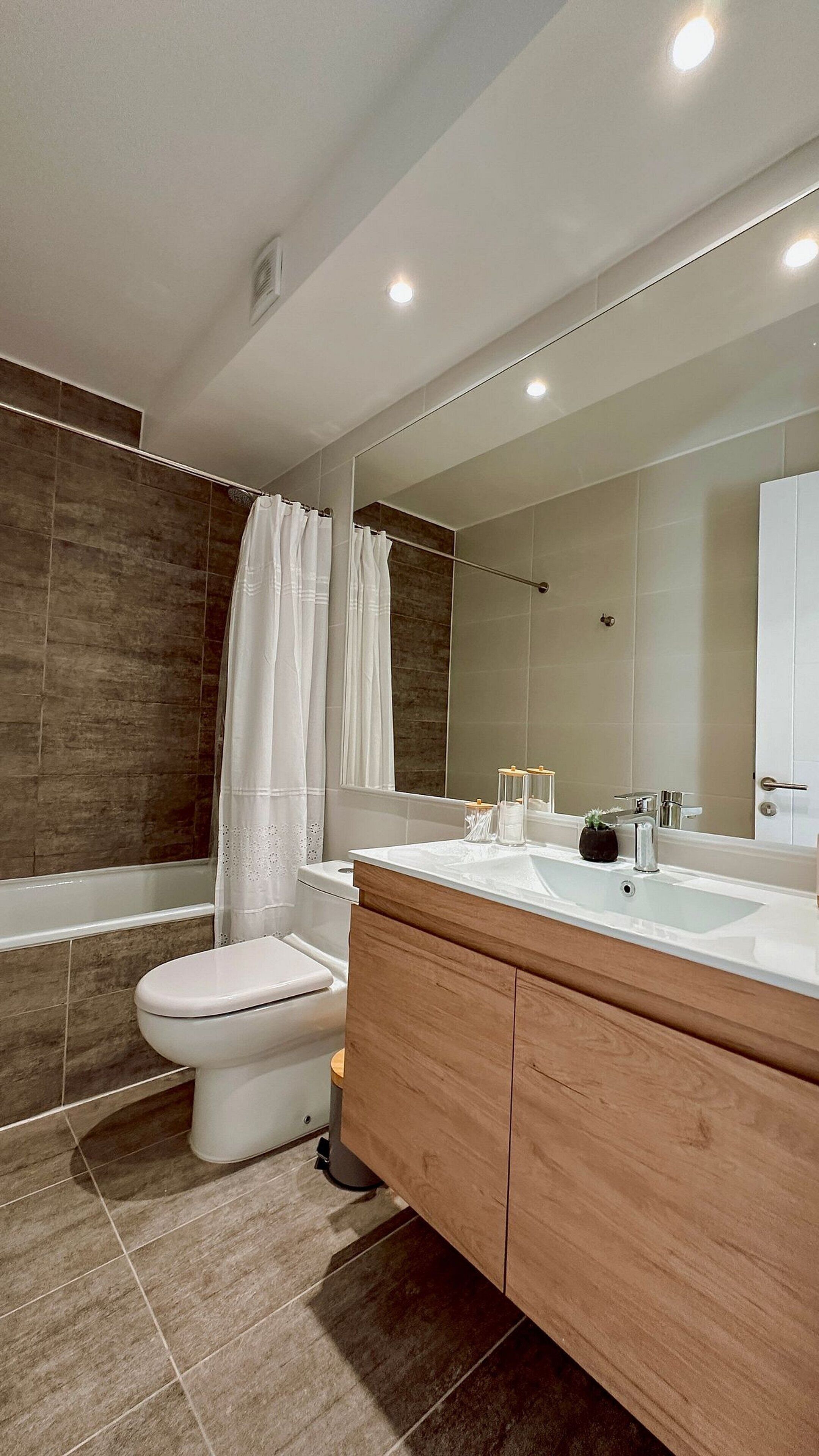 Une salle de bain moderne équipée d’une baignoire, de toilettes et d’un meuble-lavabo avec un miroir.