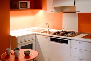 A compact kitchen with a gas stove, a sink, and a dishwasher.
