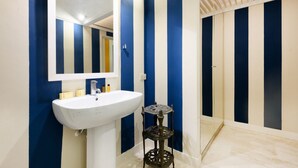 Ein Badezimmer mit einem weißen Waschbecken, einem Spiegel und einer Wand mit blauen und weißen Streifen.