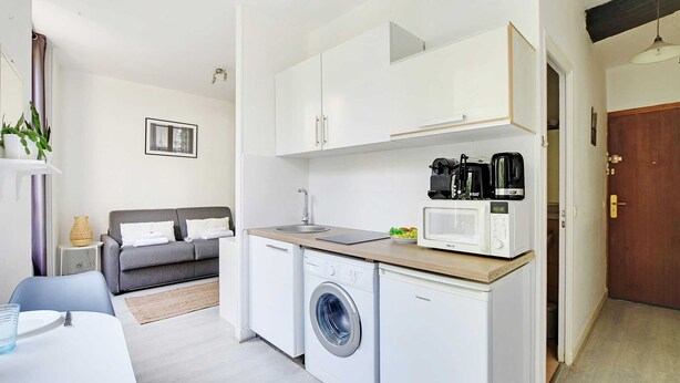 A compact kitchen with a washing machine, a microwave, and a coffee maker. - Studio in the Heart of the Marais (Paris)