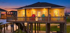 A waterfront property with a wooden deck, multiple rooms, and outdoor seating.