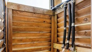 A wooden room with a slatted wall and a metal pipe running vertically.
