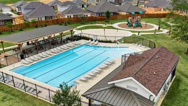 Un quartier résidentiel doté d’une piscine, de chaises longues, d’une aire de jeux et de maisons à l’architecture similaire.