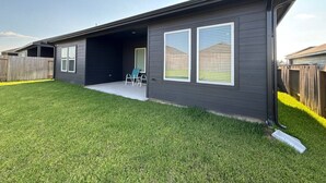 Une maison moderne à deux étages, dotée d’une fa çade sombre, d’un patio couvert et d’une pelouse bien entretenue.