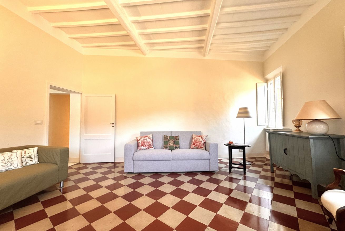 Une pièce avec un sol à carreaux, un canapé, une lampe et un meuble.