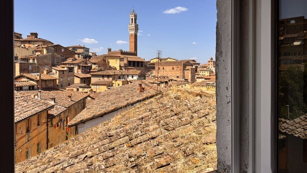 A view of a historic town with a prominent tower and terracotta-roofed buildings. - Dimora with a view of the Torre del Mangia (Siena)
