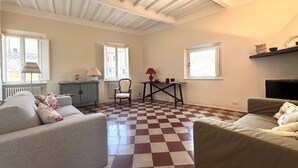 A spacious living room with a checkered floor, two sofas, a table, and a chair. - Dimora with a view of the Torre del Mangia (Siena)