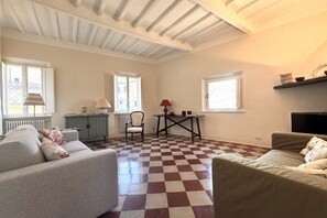 A spacious living room with a checkered floor, two sofas, a table, and a chair.