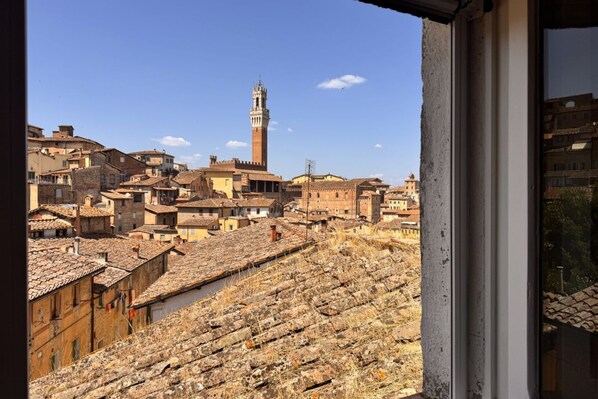 A view of a historic town with a prominent tower and terracotta-roofed buildings.