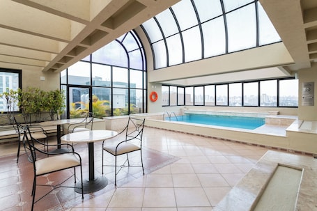 Una piscina al aire libre, sombrillas, sillones reclinables de piscina