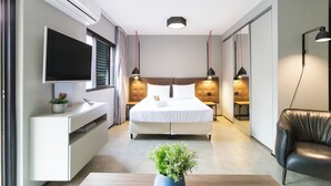 A modern hotel room with a bed, bedside lamps, a flat-screen TV, a desk, and a leather chair. - Meu Anfitrião Nações Unidas (São Paulo)