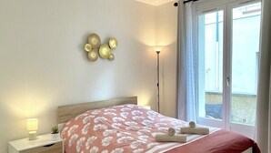 A neatly arranged bedroom with a bed, bedside table, lamp, and decorative wall pieces.