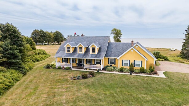 A two-story house with a porch, a chimney, and a view of a lake.