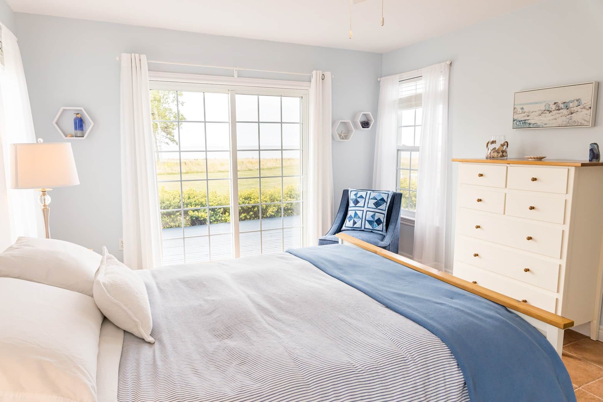 Une chambre avec un grand lit, une commode et une fenêtre avec des rideaux.