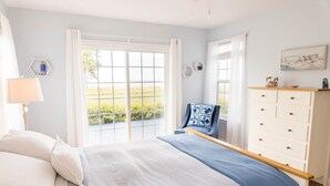 A bedroom with a large bed, a dresser, and a window with curtains.