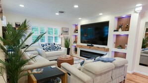 A modern living room with a sofa, a coffee table, and a flat-screen TV mounted on the wall.