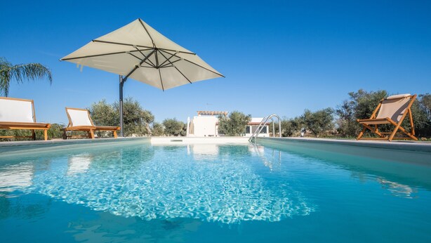 Una piscina con sillas de descanso y una sombrilla.