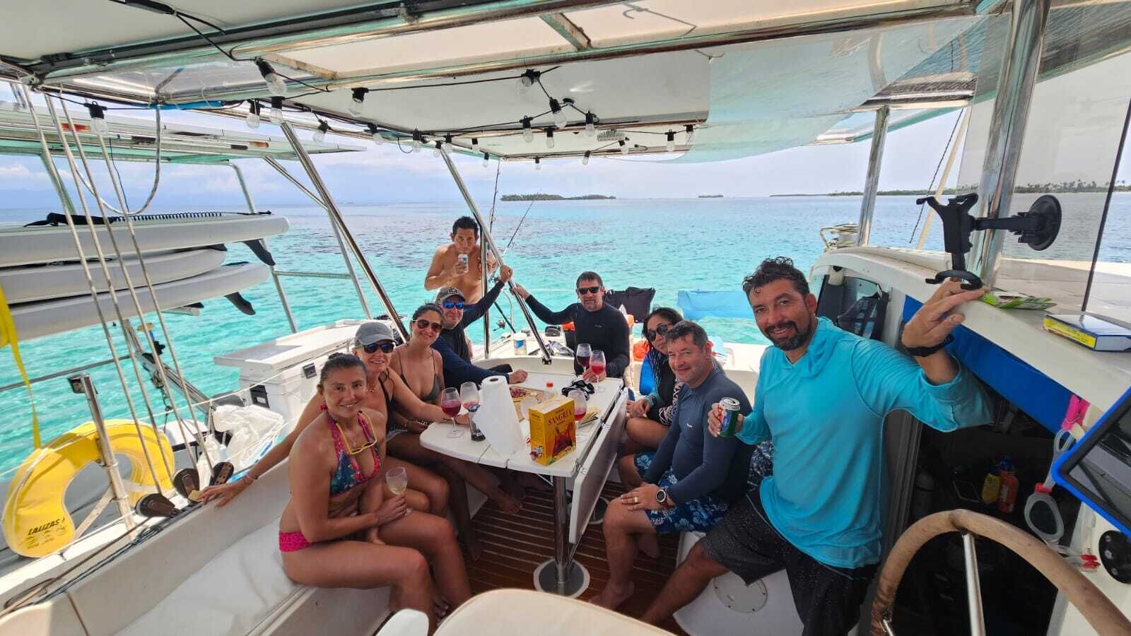 Un grup de persones en un vaixell amb una taula preparada, envoltat d'aigua i un cel serè.