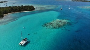 An aerial view of a turquoise sea with a small island and a boat.