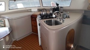 A compact kitchen with a stove, sink, and window overlooking the deck.