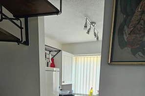 A kitchen with white cabinets, a hanging rack, and a ceiling light fixture. - Willow Retreat - House in Burbage- Sleeps2- Garden (Hinckley)