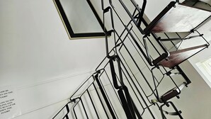 Een trap met een leuning en een bordje aan de muur.
