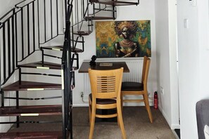 A room with a spiral staircase, a table, two chairs, and a painting on the wall. - Willow Retreat - House in Burbage- Sleeps2- Garden (Hinckley)