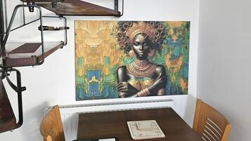 Ein Essbereich mit Tisch, Stühlen und einem Bild an der Wand.