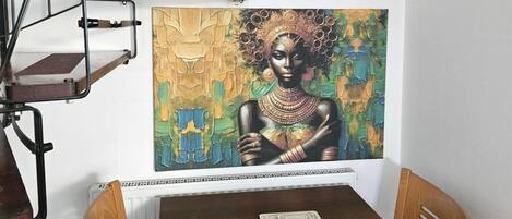 Un comedor con una mesa, sillas y un cuadro en la pared.