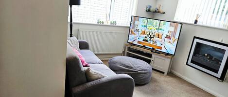 Una sala de estar con un sofá, un sillón de mimbre, un televisor y una chimenea.