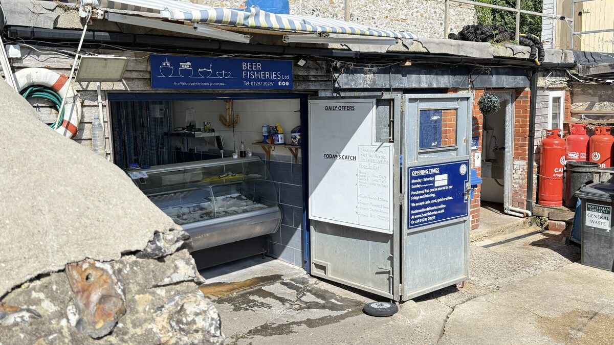 Un piccolo edificio commerciale con un cartello per 'Beer Fisheries Ltd.' e una vetrina che espone oggetti all'interno.