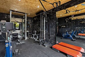 A gym with various exercise equipment, including a bench press, a squat rack, and a cable machine.