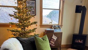 Un soggiorno accogliente con un albero di Natale, un camino e vista sull'esterno.