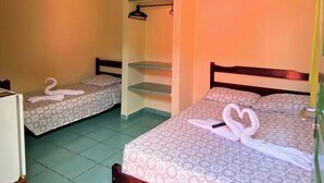 Une chambre d’hôtel avec deux lits, chacun agr émenté d’une décoration en forme de cygne faite avec des serviettes, un ventilateur de plafond et une petite étagère.