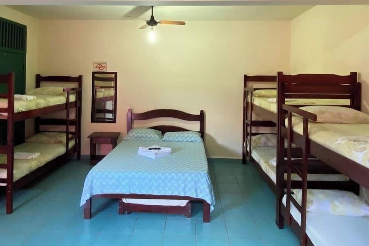A dormitory room with bunk beds, a ceiling fan, and a small table.